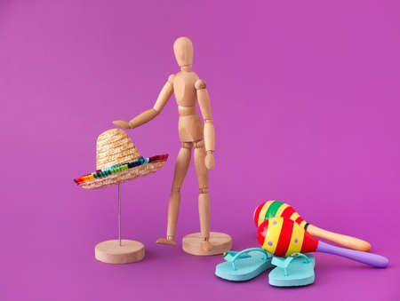 Wooden mannequin near straw sombrero on color background