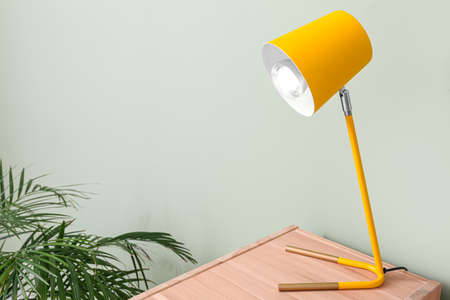 Modern lamp on wooden table near color wallの写真素材