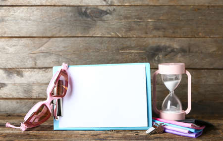 Clipboard with swimming goggles and hourglass on dark wooden background
