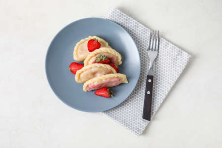 Plate with delicious strawberry dumplings on light backgroundの写真素材