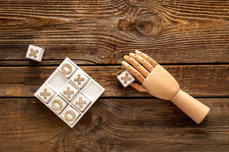 Game of Tic-Tac-Toe and decorative hand on wooden background