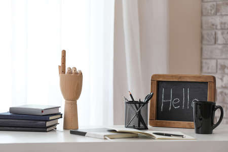 Wooden hand with stationery, chalkboard and cup on table in officeの写真素材