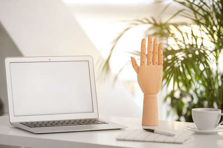 Wooden hand and laptop on table in officeの写真素材