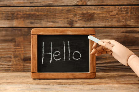 Board with word HELLO, decorative hand and chalk on wooden backgroundの写真素材