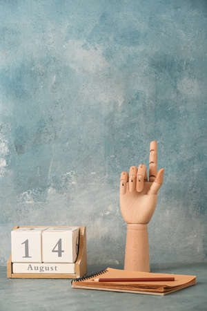 Wooden hand with pencil, notebook and cube calendar on blue backgroundの写真素材