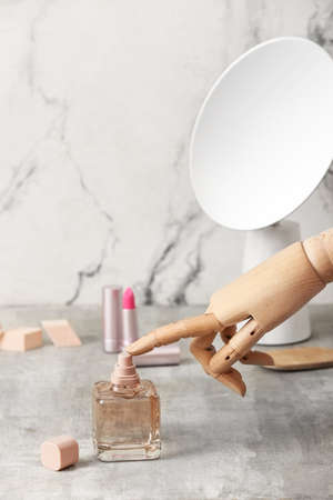 Wooden hand with bottle of perfume on light background