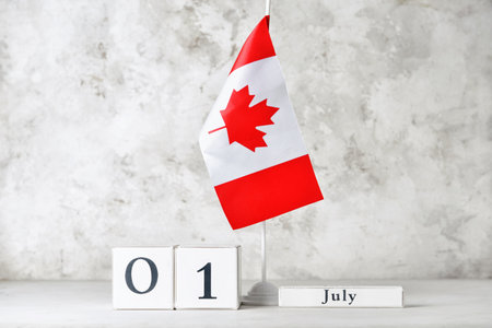 Cube calendar with date JULY 1 and flag of CANADA on table against light background. Happy Canada...