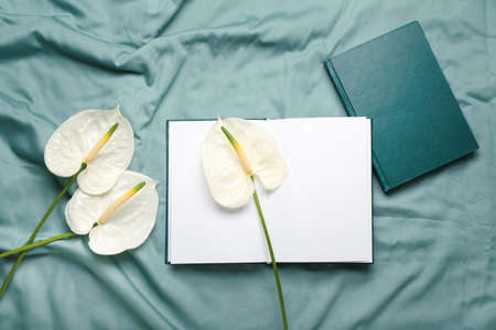 Beautiful anthurium flowers and books on fabric background