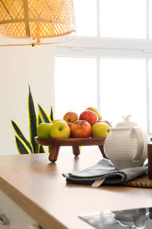 Wooden tray with fresh fruits on table in light kitchenの写真素材