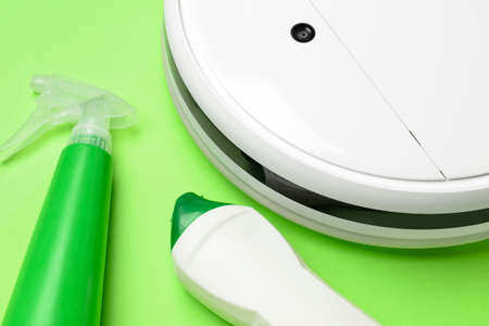 Robot vacuum cleaner, sprayer and bottle of detergent on green background, closeupの写真素材