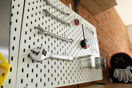 Pegboards with tools on brick wall in workshop