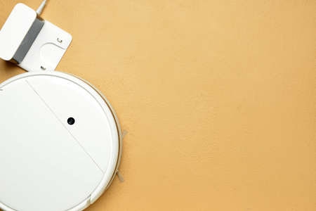 Robot vacuum cleaner and charging station on color background, closeup