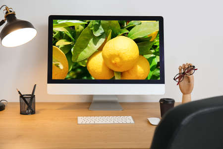 Workplace with modern computer and stationery near light wallの写真素材