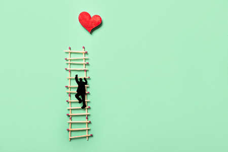 Creative composition with matches, red heart and human figure made of paper on color backgroundの写真素材