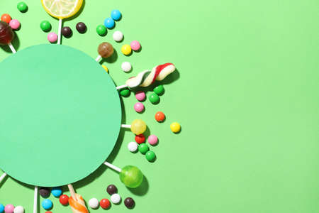 Composition with blank card, lollipops and candies on green background, closeupの写真素材