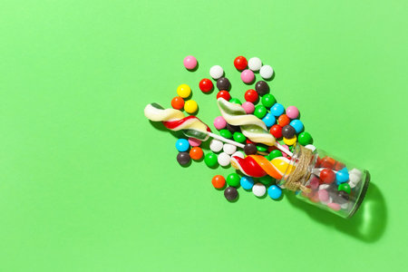 Glass jar with lollipops and candies on color backgroundの写真素材