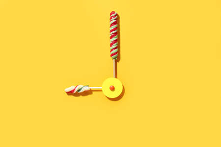 Clock made of lollipops on color backgroundの写真素材