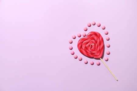 Lollipop in shape of heart and candies on color backgroundの写真素材