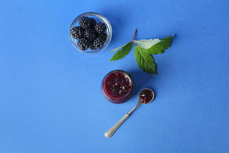 Jar of tasty blackberry jam and berries on color backgroundの写真素材