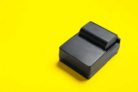 Camera battery and charger on yellow backgroundの写真素材