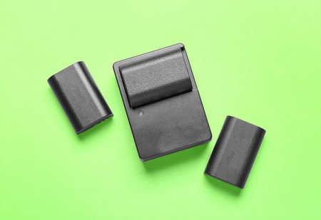 Camera batteries and charger on green background
