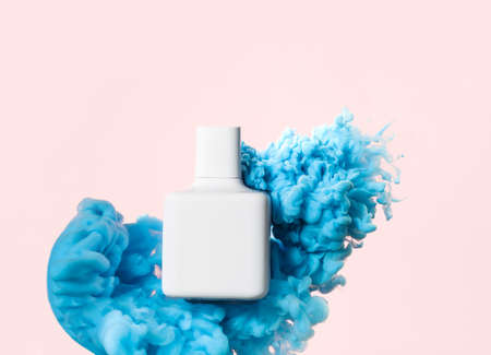 White perfume bottle in blue smoke on pink backgroundの写真素材