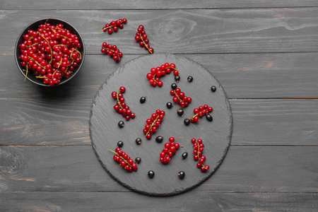 Composition with red and black currant on dark wooden background