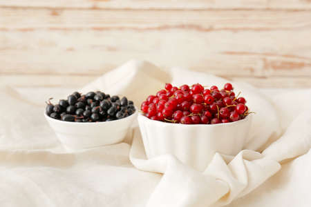 Bowls with ripe red and black currant on table, closeupの写真素材