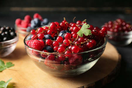 Bowl with ripe berries on wooden table, closeupの写真素材