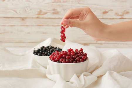 Woman eating ripe berries at table