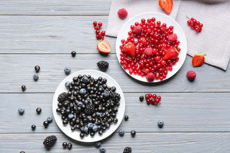Plates with tasty different berries on gray wooden backgroundの写真素材