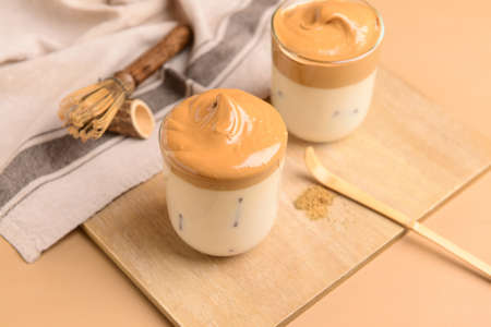 Glasses of tasty dalgona hojicha latte on color wooden background