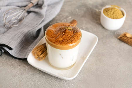 Glass of tasty dalgona hojicha latte and chasen on grunge background