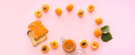 Frame made of tasty apricots, jam and toasted bread on pink backgroundの写真素材