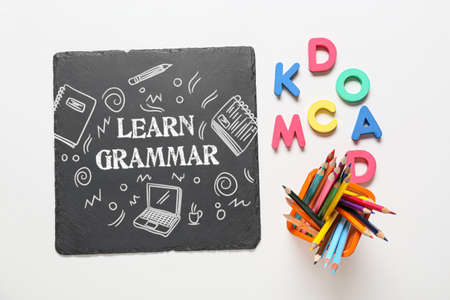Chalkboard with text LEARN GRAMMAR and different stationery on white backgroundの写真素材