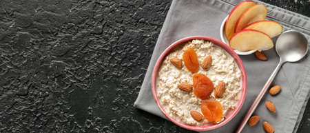 Bowl with tasty sweet oatmeal on dark background with space for textの写真素材
