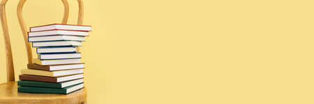 Many books on chair against yellow background. Banner design