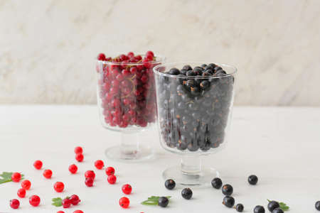 Bowls with tasty red and black currants on light backgroundの写真素材