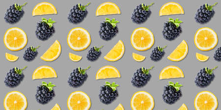 Many ripe blackberries and lemon slices on gray background. pattern for design