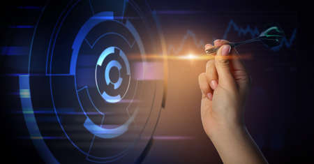 Hand of woman playing virtual darts on dark backgroundの写真素材