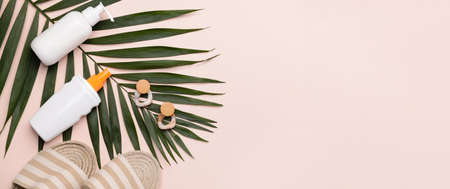 Sandals, sunscreen, tropical leaf and earrings on light background with space for text