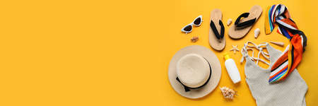 Bottle of sunscreen and beach accessories on yellow background with space for text
