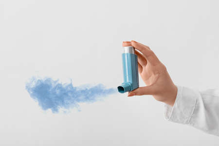 Female hand with inhaler on light backgroundの写真素材