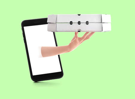 Smartphone and hand with pizza boxes on green background. food delivery