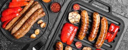 Composition with delicious grilled sausages and vegetables on black background, top view