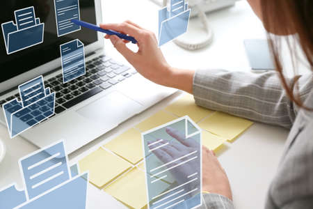 Young businesswoman with sticky note papers, laptop and digital files at her workplace