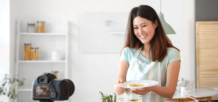 Young Asian woman recording video for food blog in kitchenの写真素材