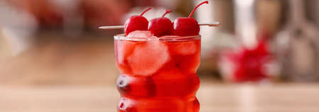 Glass of tasty Manhattan cocktail with cherry on blurred background, closeupの写真素材