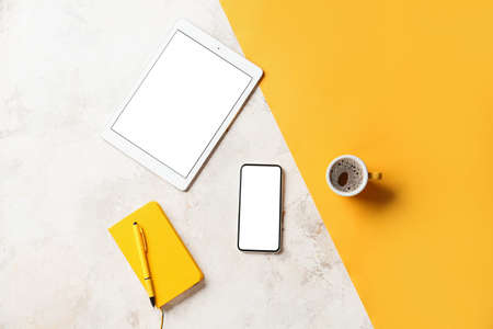 Mobile phone, tablet computer, cup of coffee, notebook and pen on color backgroundの写真素材