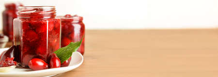 Jar of tasty dogwood jam and berries on wooden table with space for textの写真素材